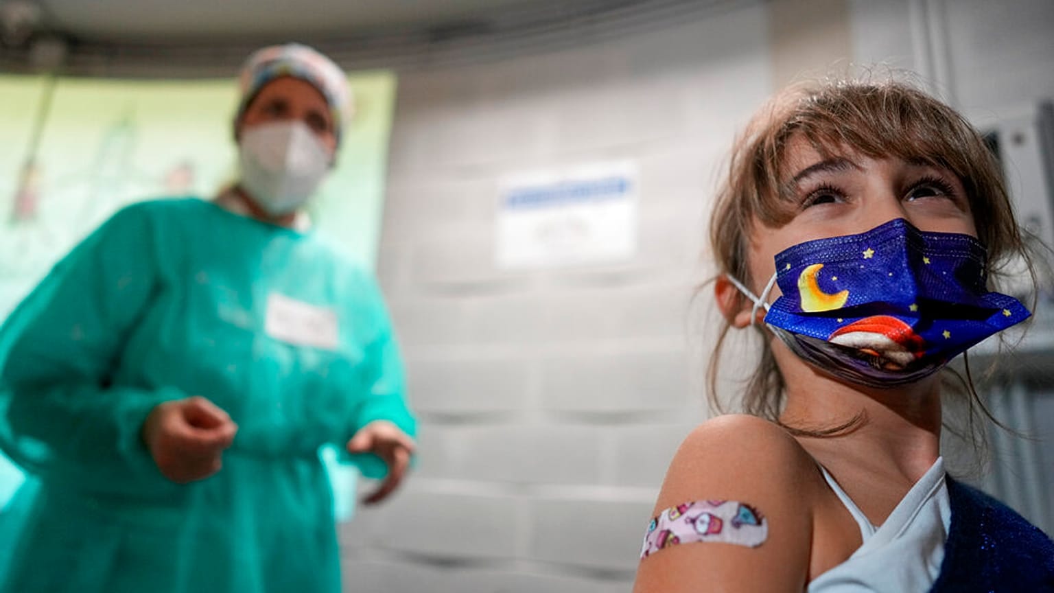 Kislány mutatja sebtapaszát, miután beoltották a Pfizer 11 év alatti gyerekeknek szánt vakcinájával Rómában, 2021. december 15-én