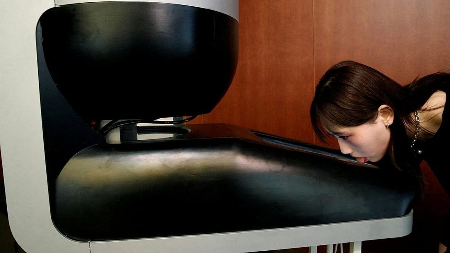 Image shows a Meiji University student demonstrating a lickable TV screen called ‘Taste the TV