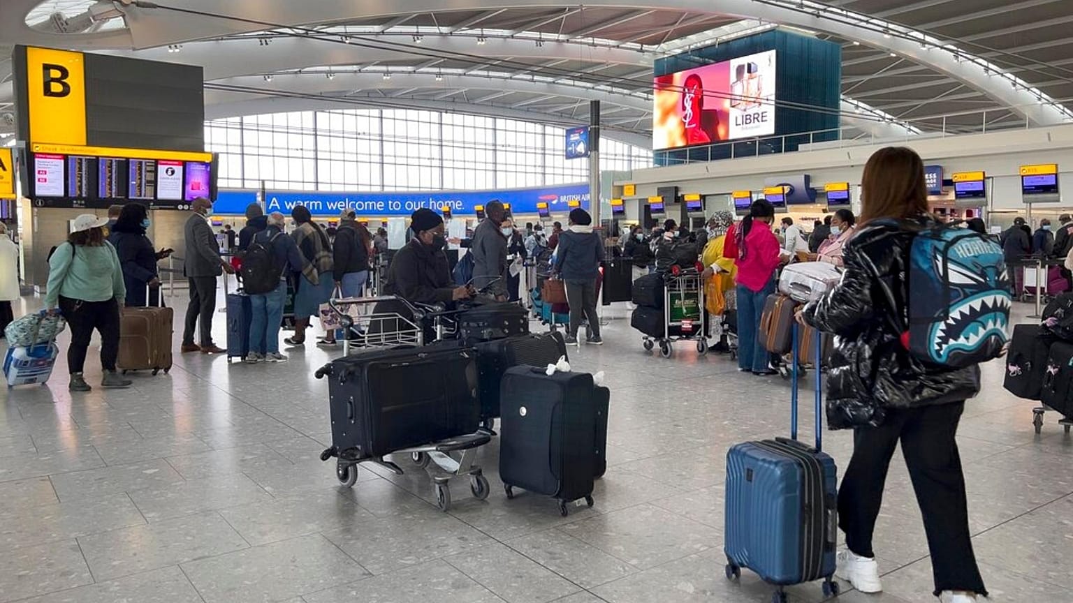 Passengers queue to check in, at Heathrow Airport in London.