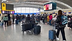 Passengers queue to check in, at Heathrow Airport in London.