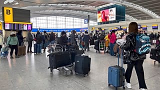 Passengers queue to check in, at Heathrow Airport in London.