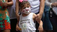 "Vacinação Infantil, Já!", lê-se numa blusa envergada por criança durante a manifestação pelas vacinas contra a covid-19