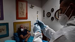 Nurse Luigi Lauri prepares a dose of the Pfizer vaccine for 85-year old Giorgio Tagliacarne at his home in Rome, Tuesday, April 27, 2021