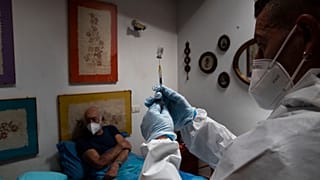 Nurse Luigi Lauri prepares a dose of the Pfizer vaccine for 85-year old Giorgio Tagliacarne at his home in Rome, Tuesday, April 27, 2021
