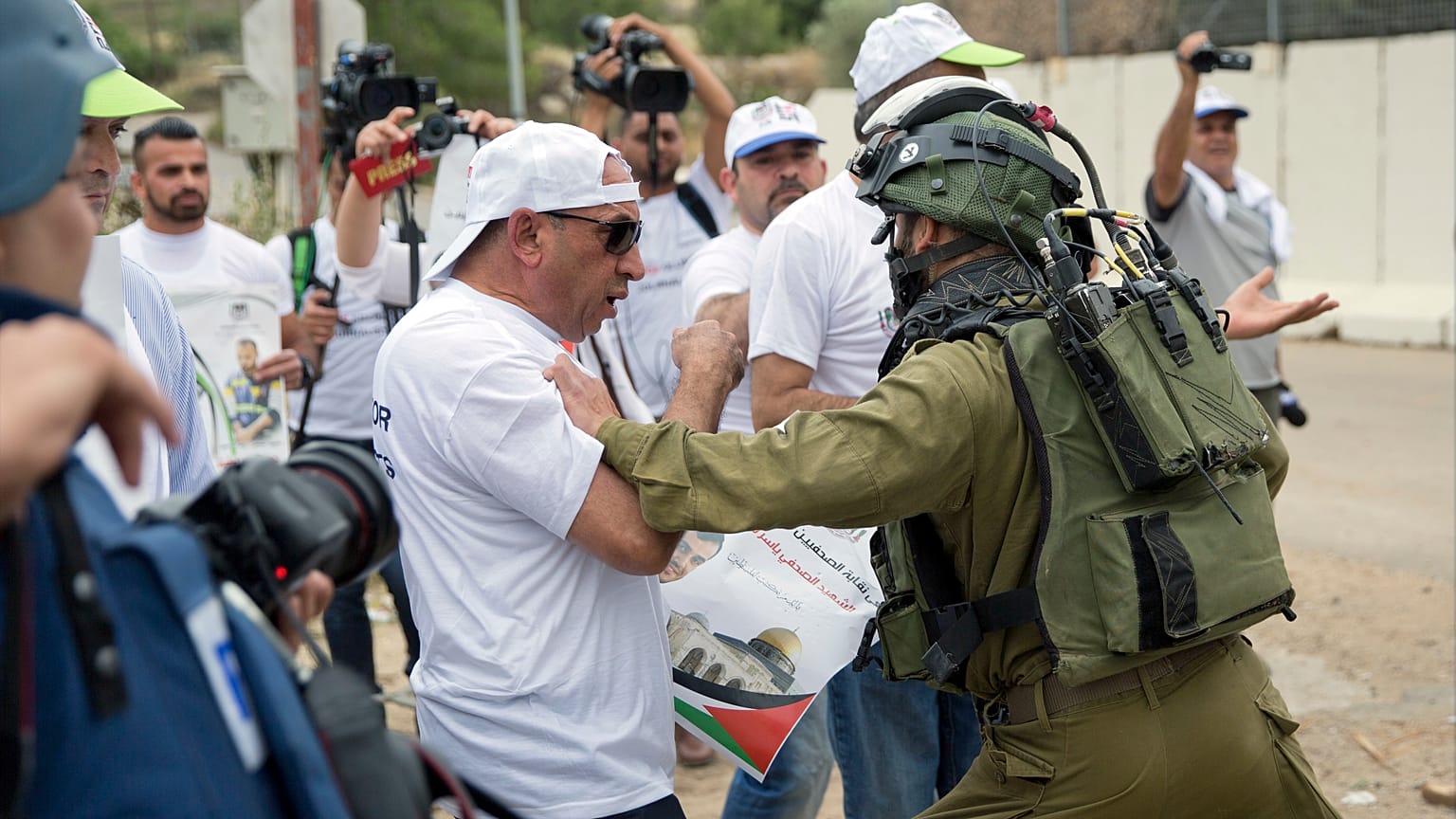 جندي إسرائيلي يدفع صحفي  فلسطيني، خلال مظاهرة نظمتها نقابة الصحفيين الفلسطينيين  بالقرب من مدينة رام الله الضفة الغربية.