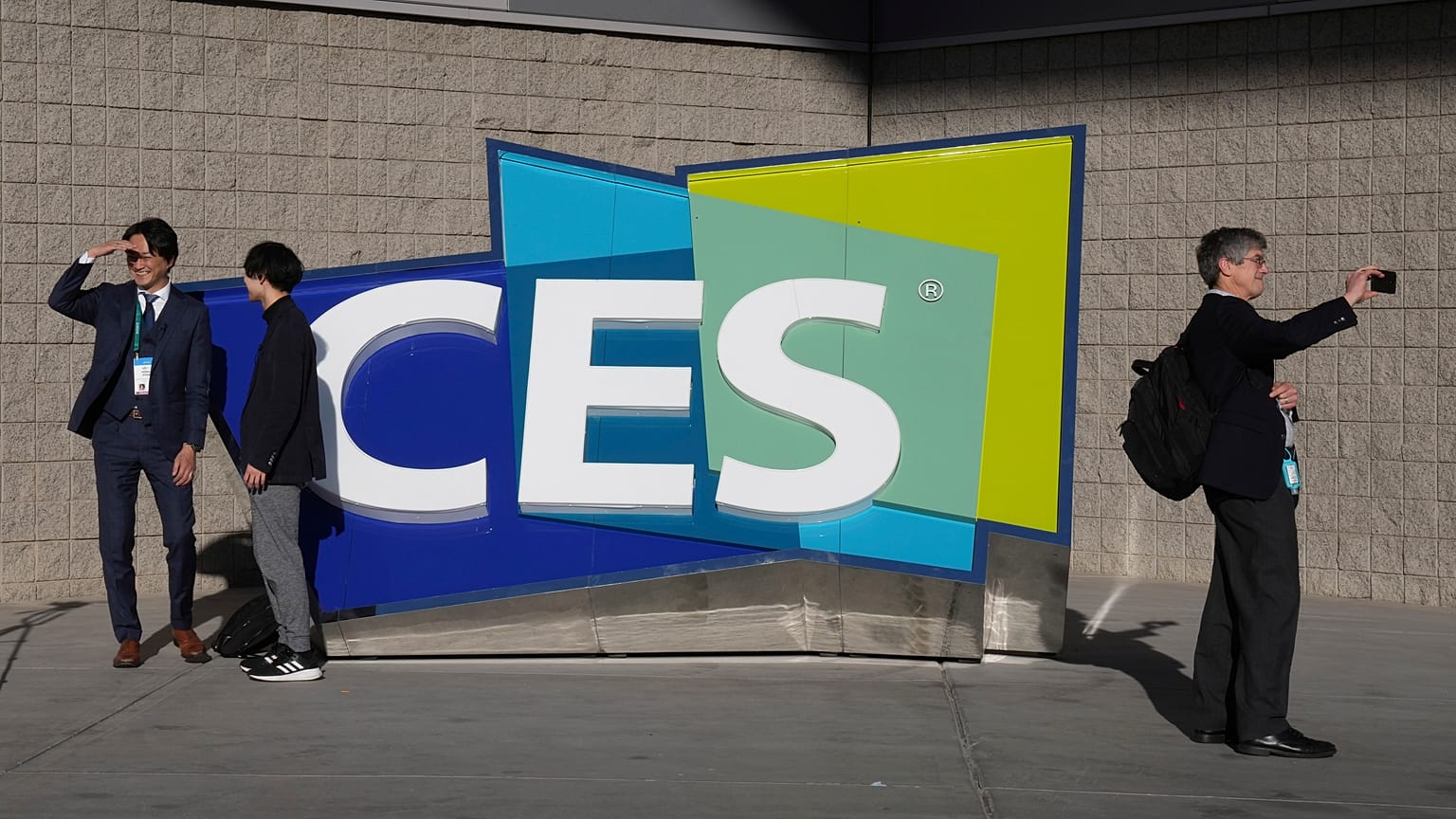 People take pictures in front of a sign during the CES tech show Thursday, Jan. 6, 2022, in Las Vegas.