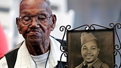 WWII veteran Lawrence Brooks holds a photo of him taken in 1943, as he celebrates his 110th birthday at the National World War II Museum in New Orleans, on Sept. 12, 2019.