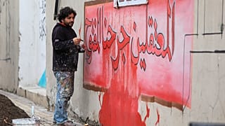 الفنان السوري عزيز أسمر يرسم جدارية كتب عليها "المعتقلون جرحنا المفتوح" حيث يشارك أهالي وأقارب المعتقلين والمفقودين في مسيرة للمطالبة بالإعلام عن ذويهم، في بلدة أعزاز.