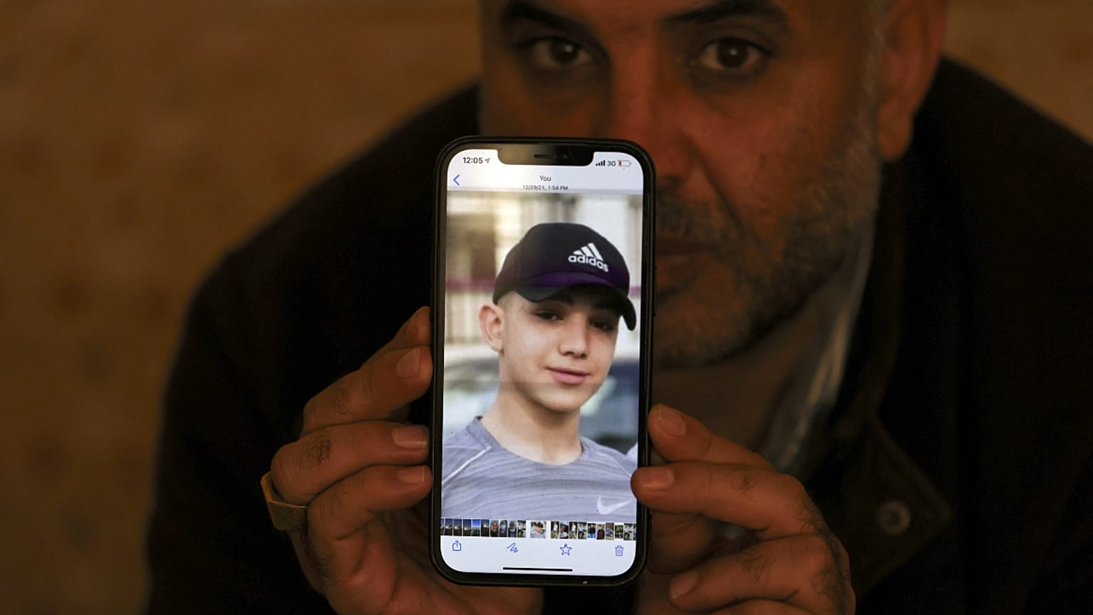 والد أمل يحمل صورة ابنه