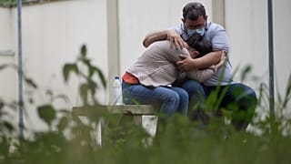 A couple embraces as they wait for information about missing relatives after a massive slab of rock toppled onto pleasure boaters at Furnas reservoir on Saturday
