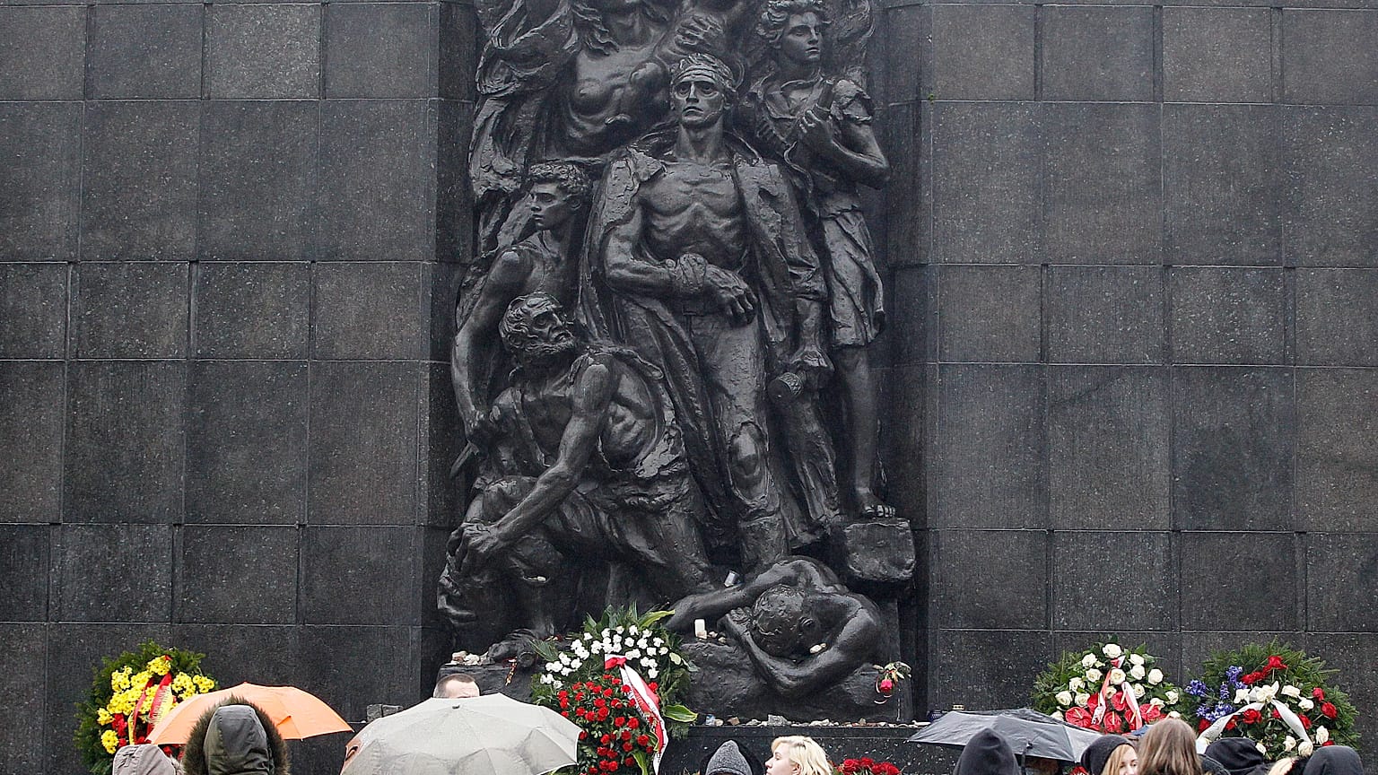 Tourists gather in front of the monument to the Heroes of the Warsaw Ghetto who fought in the 1943 uprising.