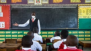 A teacher welcomes back students during a classroom lesson on day one of re-opening schools in Kampala, Uganda.