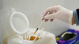 A nurse puts a used syringe into a box at an Italian Red Cross vaccination hub in Rome.