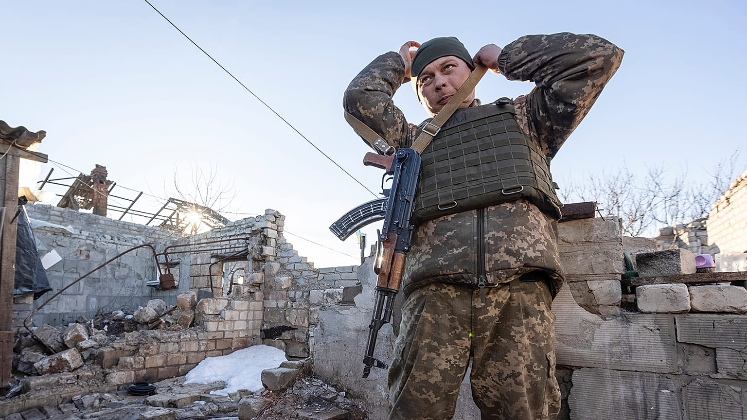 A Ukrainian soldier adjusts his gun near the ruined house at a line of separation from pro-Russian rebels in Donbas