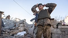 A Ukrainian soldier adjusts his gun near the ruined house at a line of separation from pro-Russian rebels in Donbas