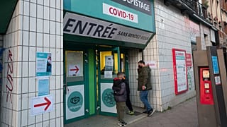 A man with children walks into a COVID-19 testing site in Lille, northern France, Tuesday, Jan. 11, 2022.