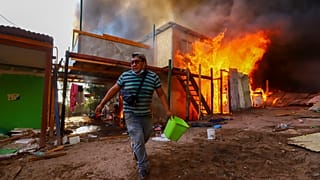 Un vecino ayuda a apagar el incendio de Laguna Verde, en la ciudad chilena de Iquique, el lunes 10 de enero