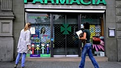 People stop in front of a closed pharmacy in Barcelona.