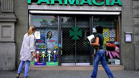 People stop in front of a closed pharmacy in Barcelona.