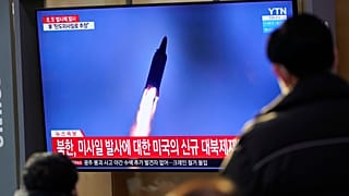 People watch a TV screen showing a news program reporting about North Korea's missile launch with a file image, at a train station in Seoul, South Korea, Jan. 14, 2022.