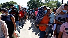 Migranten stehen Schlange und darauf, dass ihre Dokumente von der Polizei in Corinto, Honduras, überprüft werden (15. Januar 2022).