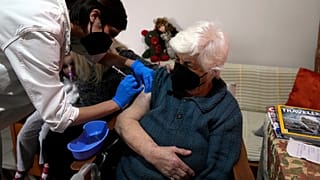 ممرّضة تقدّم جرعة ثانية من لقاح فايزر لمسنّة تجاوزت الـ 90 من عمرها، في منزلها بأثينا، الأربعاء ، 22 ديسمبر، 2021