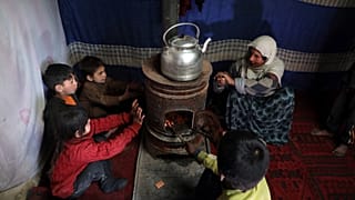 أطفال نازحون يجلسون حول موقد للتدفئة في ملجأ مؤقت في مدينة كابل، أفغانستان2020/12/30