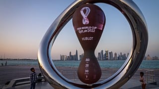 أطفال بالقرب من ساعة العد العكسي الرسمية لمونديال قطر 2022 في الدوحة