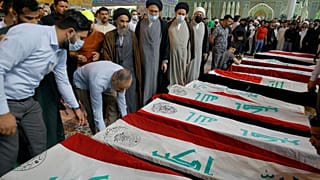 Mourners pray over the flag-draped coffins of civilians killed in an attack by the Islamic State extremist group in the village of al-Rashad, Oct. 27, 2021.