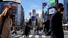 People wearing protective masks to help curb the spread of the coronavirus walk along a pedestrian crossing on Friday, Jan. 21, 2022, in Tokyo.