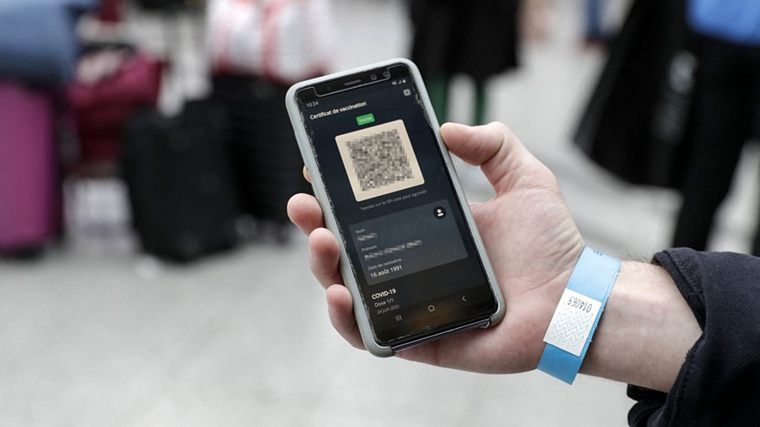 A passenger shows his Covid-19 health pass on a mobile phone at a French train station.