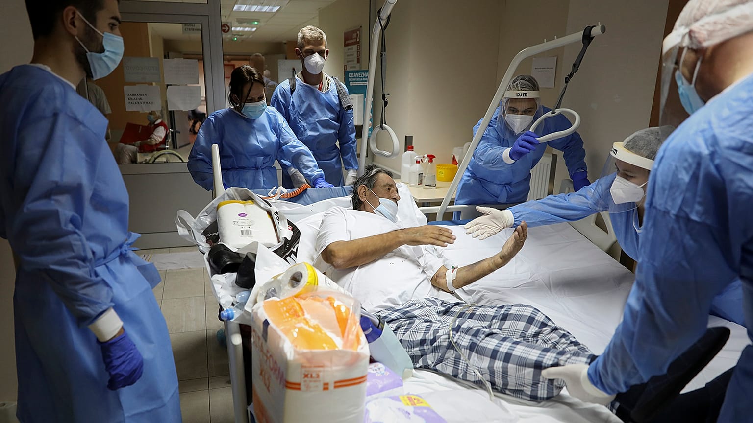 Medical staff helps a patient move to another bed in the COVID-19 section of the University Clinical Centre hospital in Banjaluka