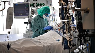 Un sanitario atiende a un paciente con COVID-19 en la UCI de la Clínica Universitaria, en Pamplona (España).