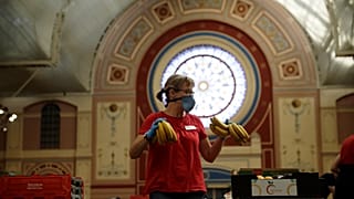 A volunteer for the Edible London food project checks bananas to be put in food packs and delivered to residents who need it in the Haringey Council area on April 21, 2020.