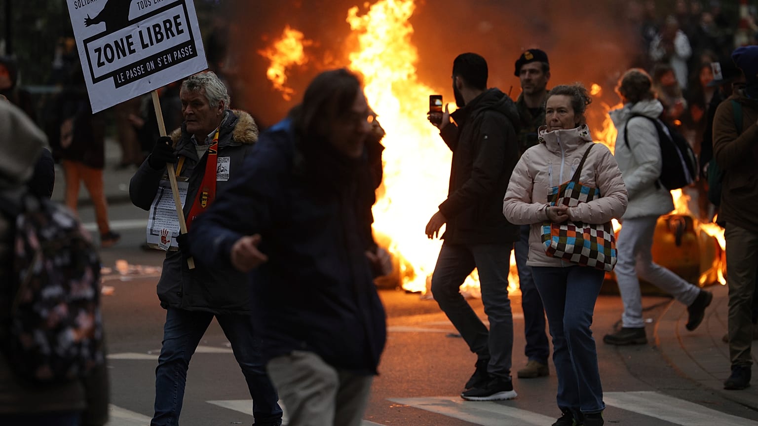 Protestors wave signs near a burning fire as they demonstrate against COVID-19 measures in Brussels, Sunday, Jan. 23, 2022. 