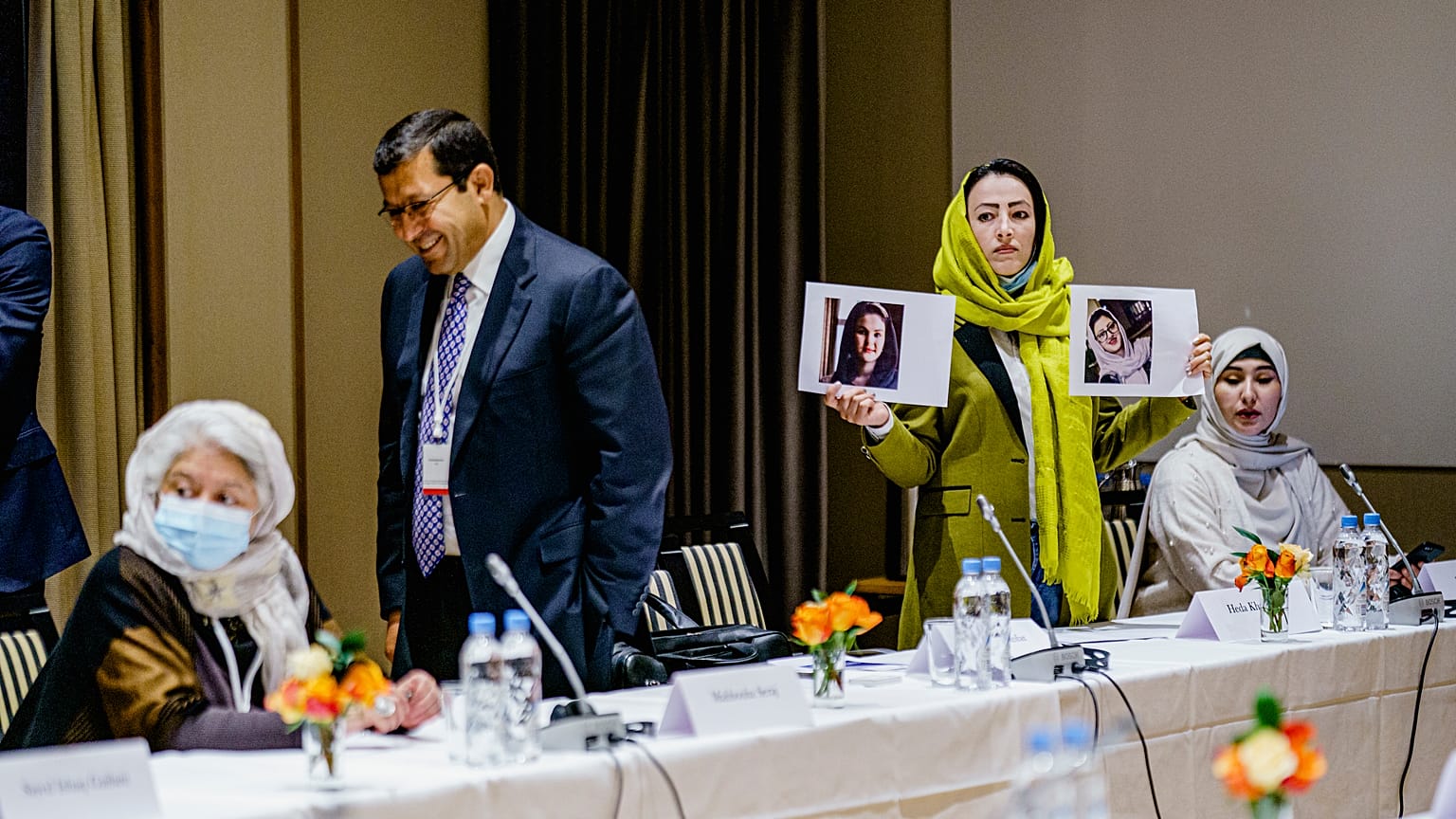 Heda Khamoush, a delegate from Afghan civil society to talks with Western diplomats, holds up photos of two women who have vanished on Monday