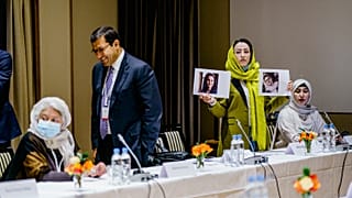 Heda Khamoush, a delegate from Afghan civil society to talks with Western diplomats, holds up photos of two women who have vanished on Monday