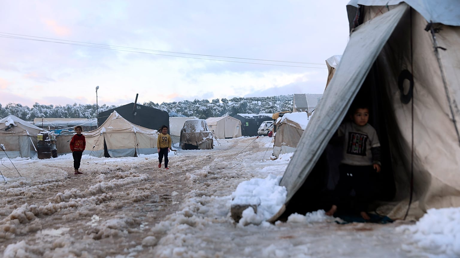 Displaced Syrian children walk in the snow at a refugee camp, in Afrin, north of Aleppo, Syria, on 19 January 2022.