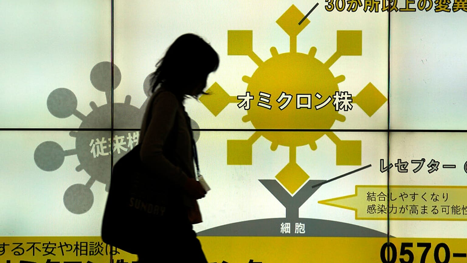 Japán nő sétál el a Tokió egyik aluljárójában elhelyezett, a koronavírusról szóló ismertetők előtt