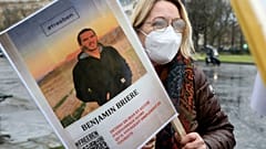 A woman holds a photo of Benjamin Briere during a rally in Paris earlier this month.