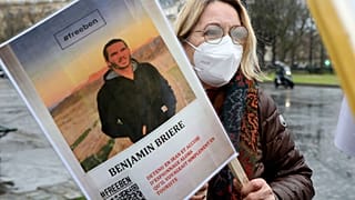 A woman holds a photo of Benjamin Briere during a rally in Paris earlier this month.
