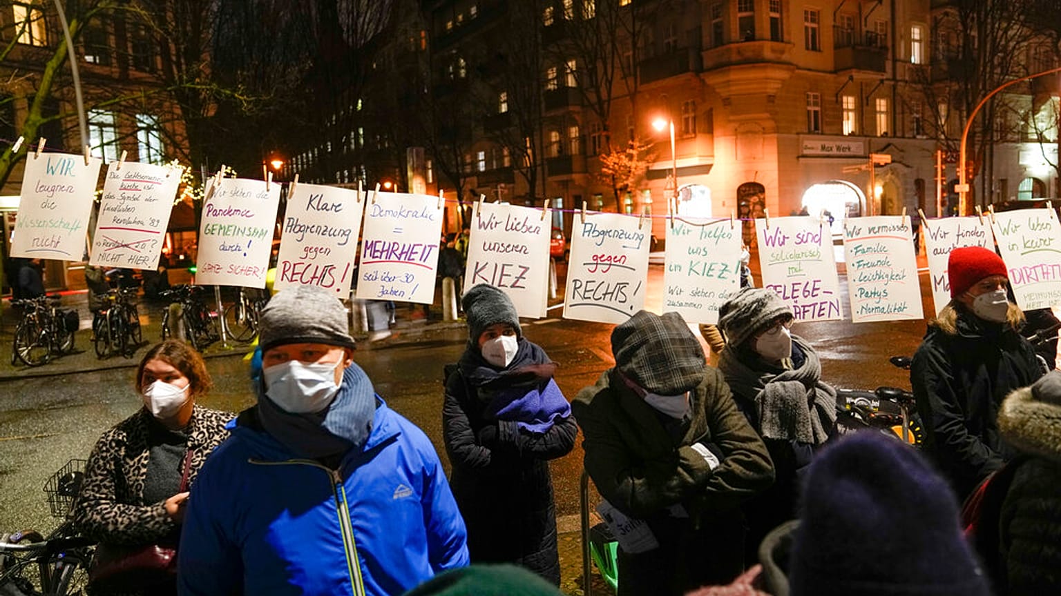 People wearing face masks stand next to posters calling for people to stick to coronavirus measures.