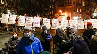 People wearing face masks stand next to posters calling for people to stick to coronavirus measures.