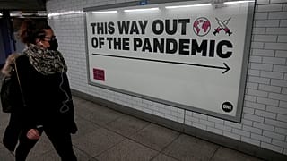 Une femme passe devant l'affiche de campagne de l'ONG One à Londres, affiche qui dit "par ici pour la sortie de la pandémie", le 27 janvier 2022