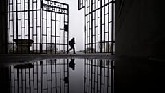 A person walks behind the gate of the Sachsenhausen Nazi death camp with the phrase 'Arbeit macht frei' in Oranienburg, Berlin