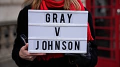 An anti-Boris Johnson protester holds a placard as a reference to the Sue Gray report, on the junction of Parliament Street and Parliament Square, in London, Jan. 26, 2022.