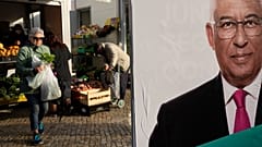 People buy groceries next to an election campaign poster in the outskirts of Lisbon