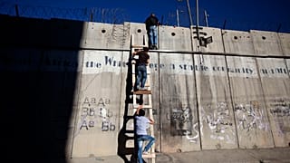 Палестинцы забираются на заграждения между Израилем и Западным берегом реки Иордан, чтобы помолиться, обратившись к мечети аль-Акса. 11 июля 2014