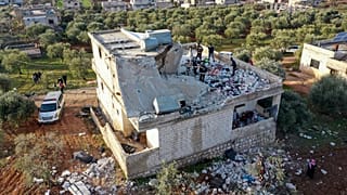 People inspect the destroyed house in Atmeh following the US operation.