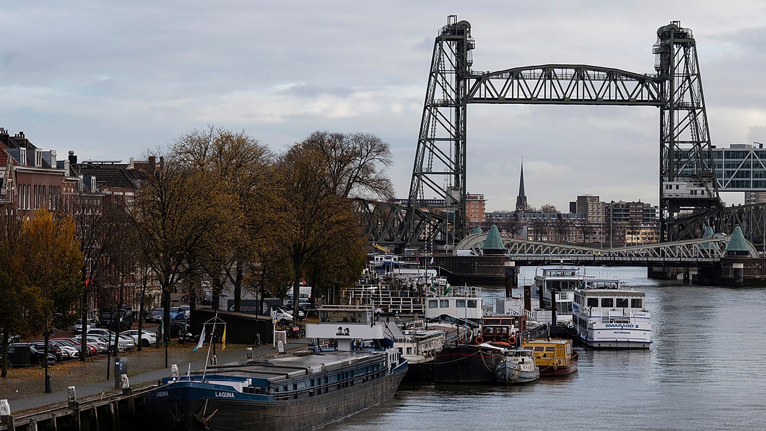 Barges docked on the Rotterdam Koningshaven waterway with the "De Hef" bridge in the background